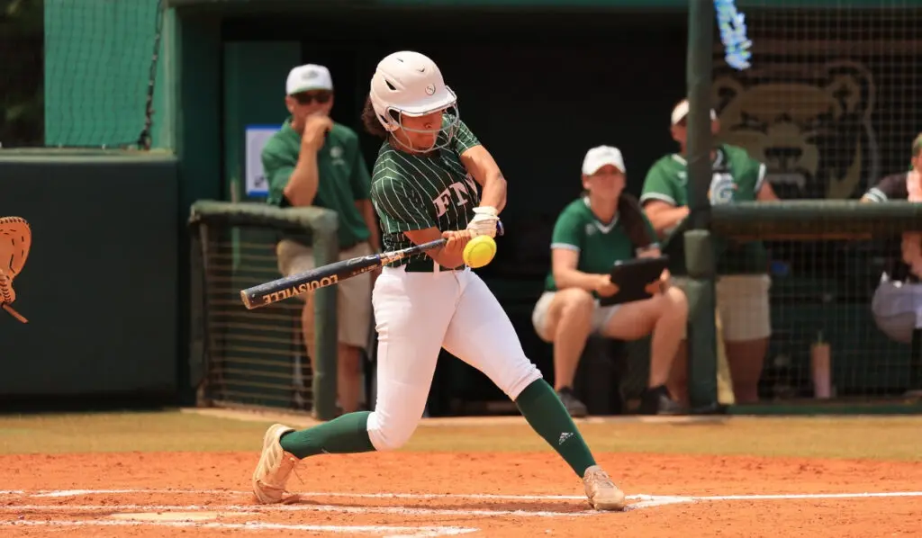 FNU softball player Ana De Oliveira Obando swinging a bat.