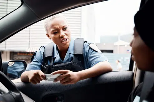 police officer in window of a car talking to driver holding their drivers license