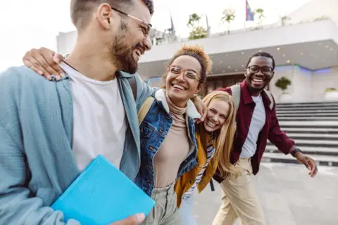 college students walking in front of a school laughing