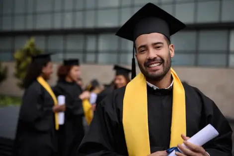 student graduating with black graduation gown and yellow scarf