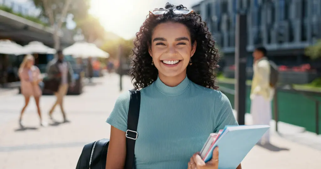 College student carrying books and a backpack on campus, representing personal growth, academic success, and career preparation at Florida National University