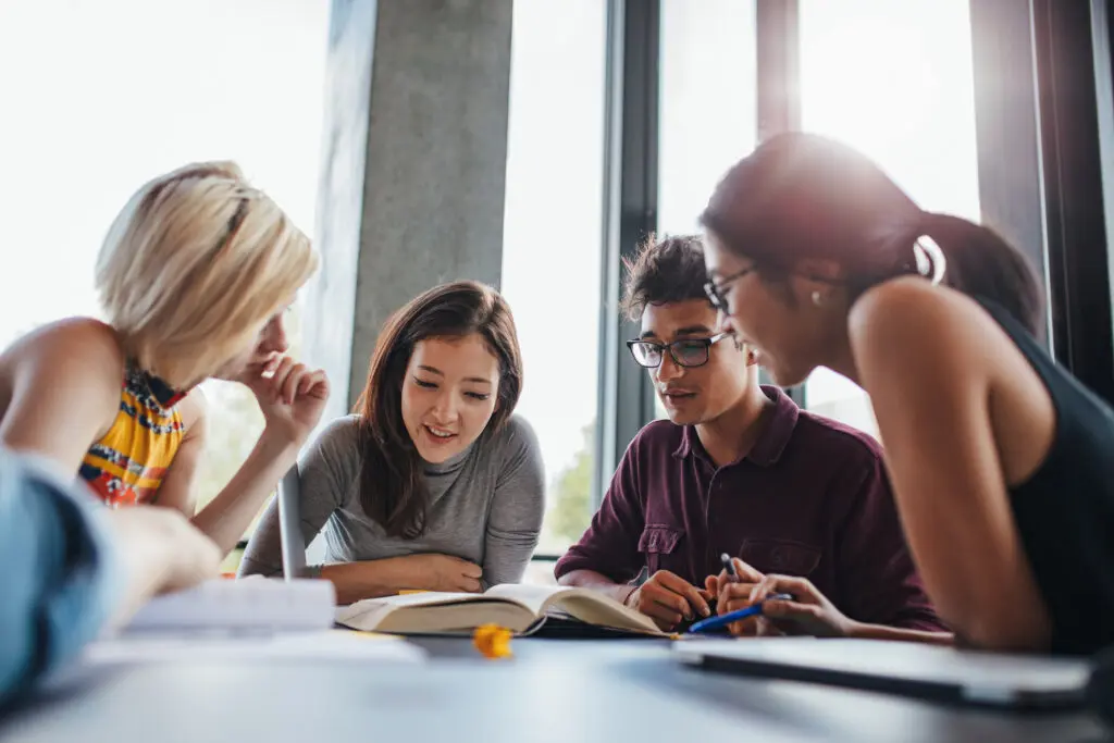 Diverse group of college students studying together in a bright, modern space, collaborating on coursework and developing teamwork skills at Florida National University.