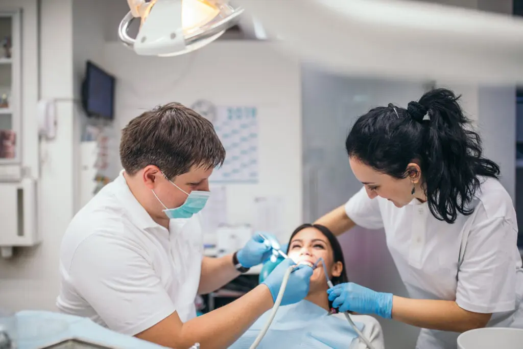 dentist and dental assistant performing a procedure on a patient in a dental office