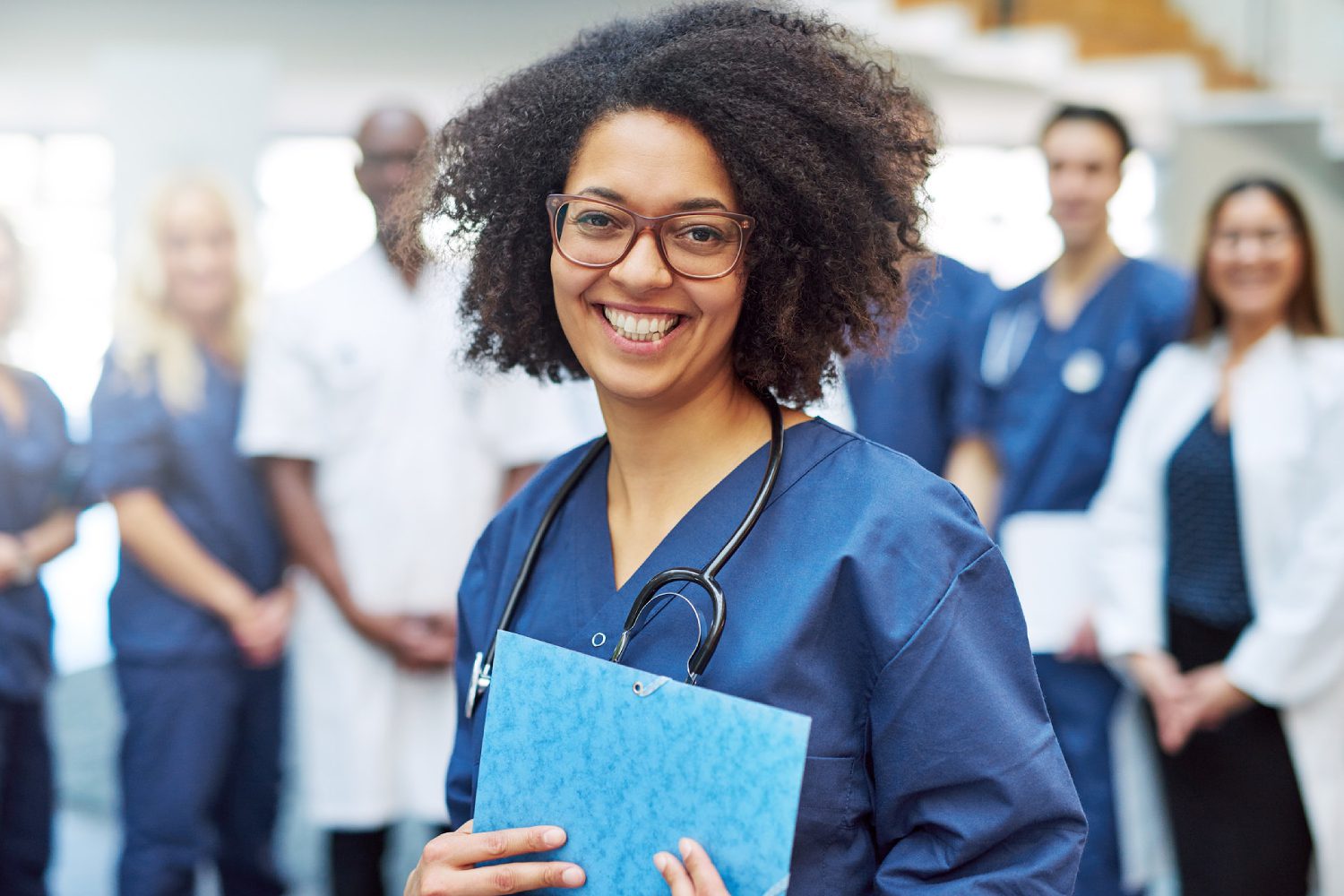 A nurse smiling with a folder in front of a group of people.