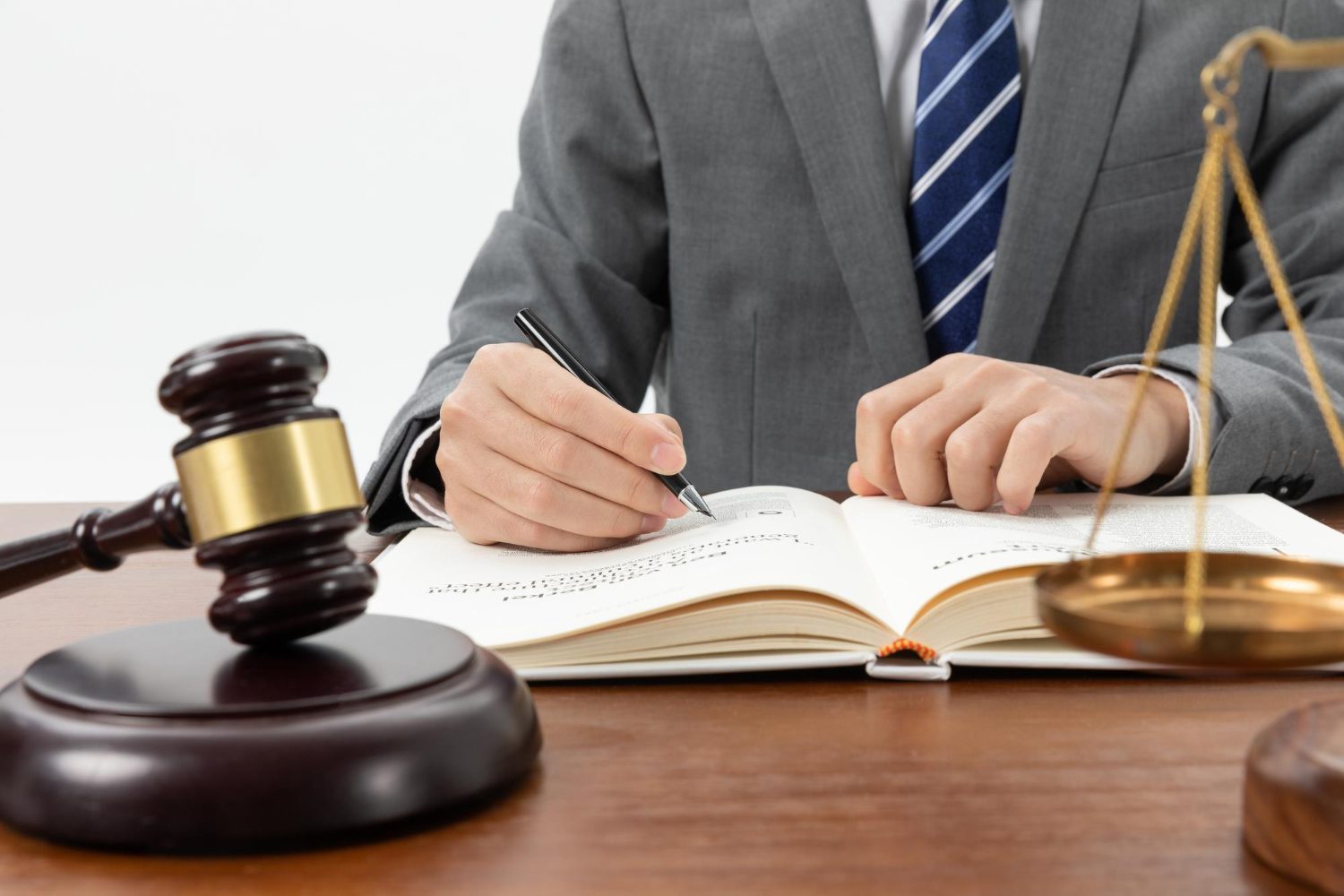 Close-up shot of a person writing a book with a gavel on the table.