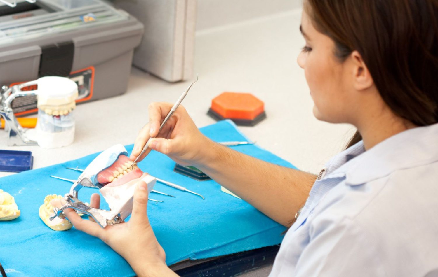 Portrait of a focused and skilled female dental laboratory technician at work. With precision and dedication, she meticulously handles dental materials and instruments, showcasing her expertise in the craft. The image highlights the professionalism and capability of women in the role of dental lab tech associates.