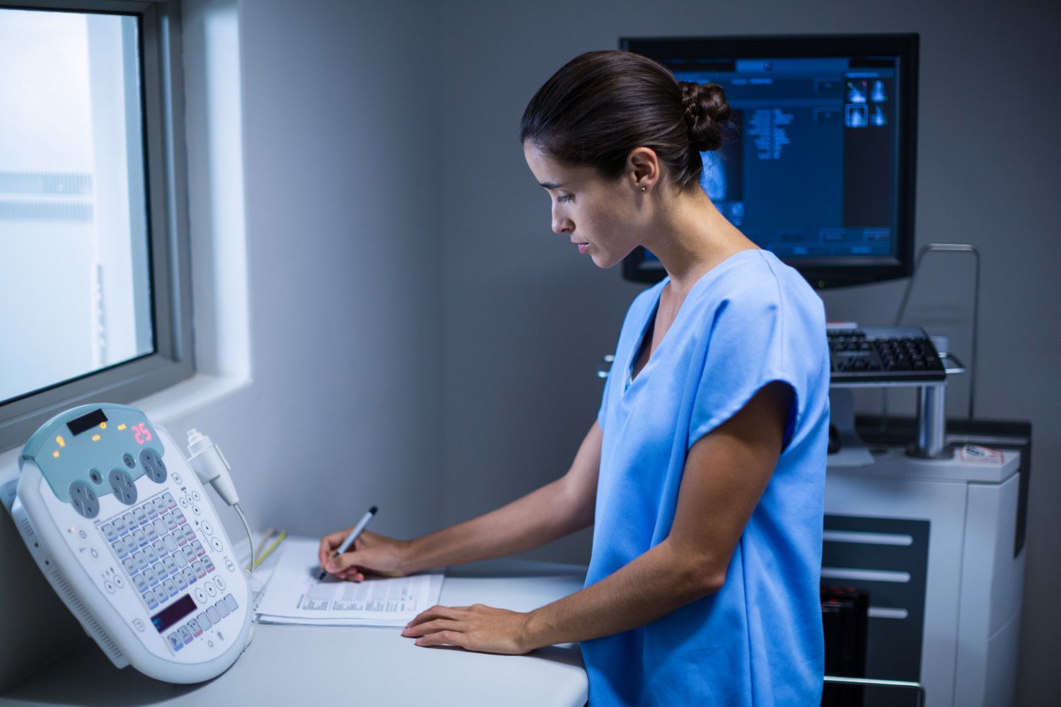 Nurse taking notes in x-ray room at hospital