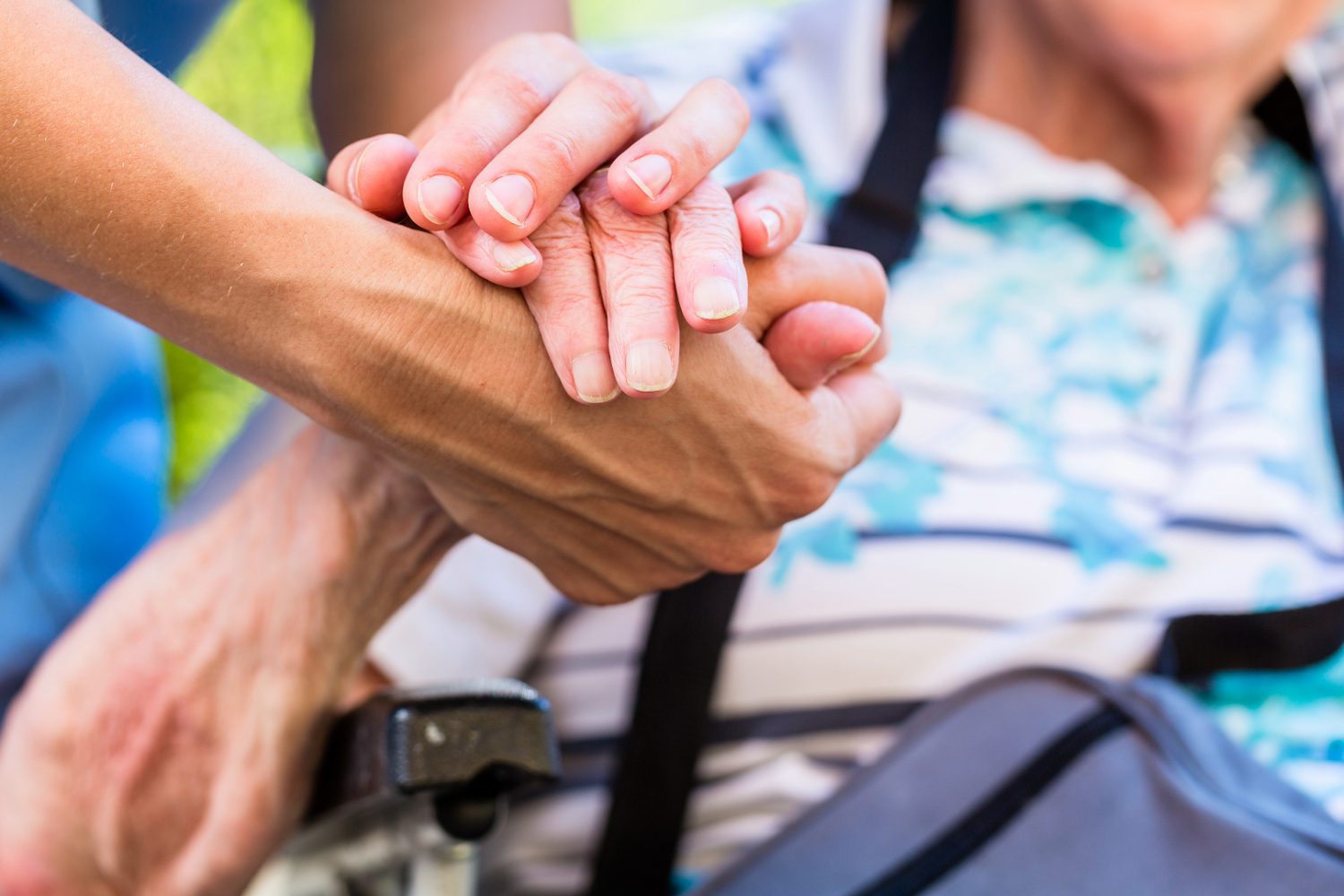 Touching photograph illustrating a caring individual assisting an elderly woman in a wheelchair. The scene exudes compassion and support as the helper guides the wheelchair, symbolizing the importance of empathy and assistance in the context of elderly care. The image captures the essence of companionship and the dedication to ensuring the well-being and mobility of the elderly within our communities.